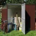 Vrtna uta Maxy Ruby 36 x 12 m odprta kaže shranjene predmete kot so vrtno orodje in kolesa postavljena na trato ob obrezani živi meji