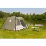 Šotor za kampiranje Instant Tourer 4 postavljen ob jezeru v naravnem okolju s piknik mizo v ospredju idealen za družinske izlete