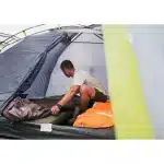 Moški v šotoru Coleman Darwin 4+ pripravlja spalno opremo prikazuje notranjost šotora in njegovo uporabnost za kampiranje