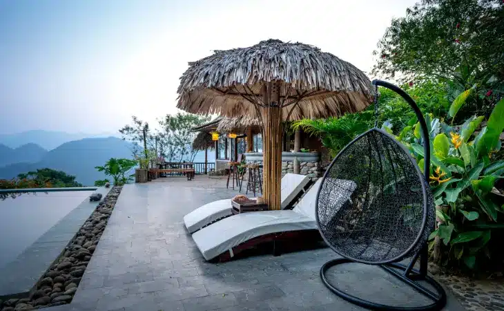 Ležalniki in gugalnik iz poliratana ob bazenu.