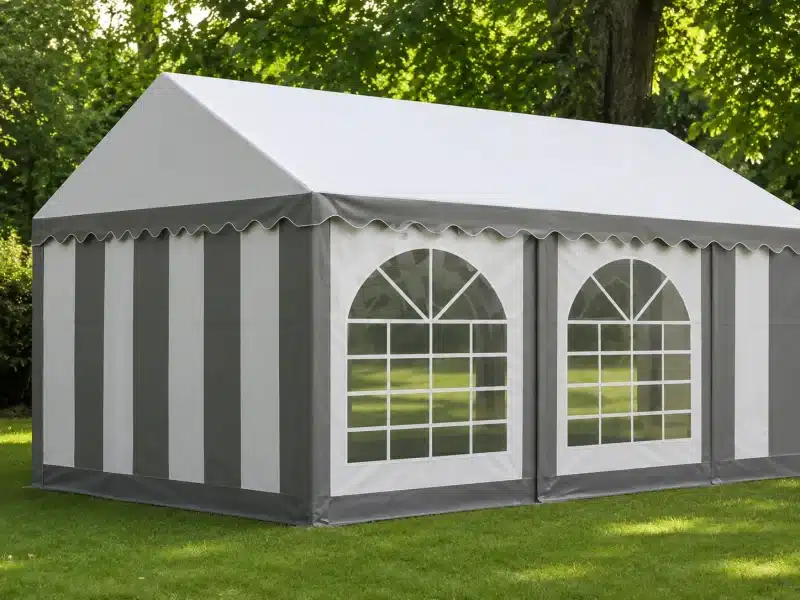 Grey and white striped event tent with arched windows on a grassy lawn