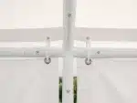 Close up of a white garden canopy frame with ringed curtain hooks and fabric panels outdoors