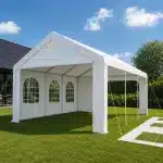 White outdoor party tent set up on a green lawn with arched window panels along the side wall under a blue sky