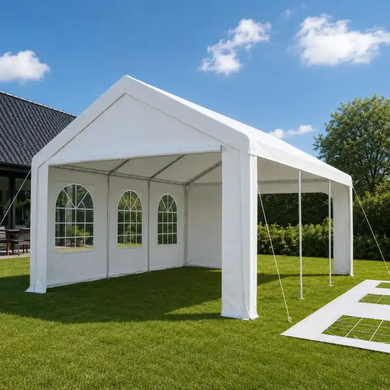 White outdoor party tent set up on a green lawn with arched window panels along the side wall under a blue sky