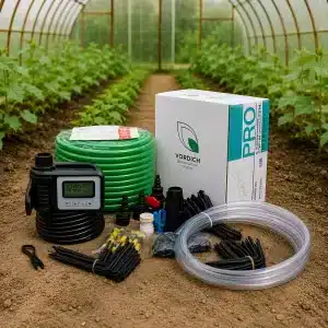 Drip irrigation kit laid out on soil in a greenhouse with timer green hose tubing and fittings beside a boxed system