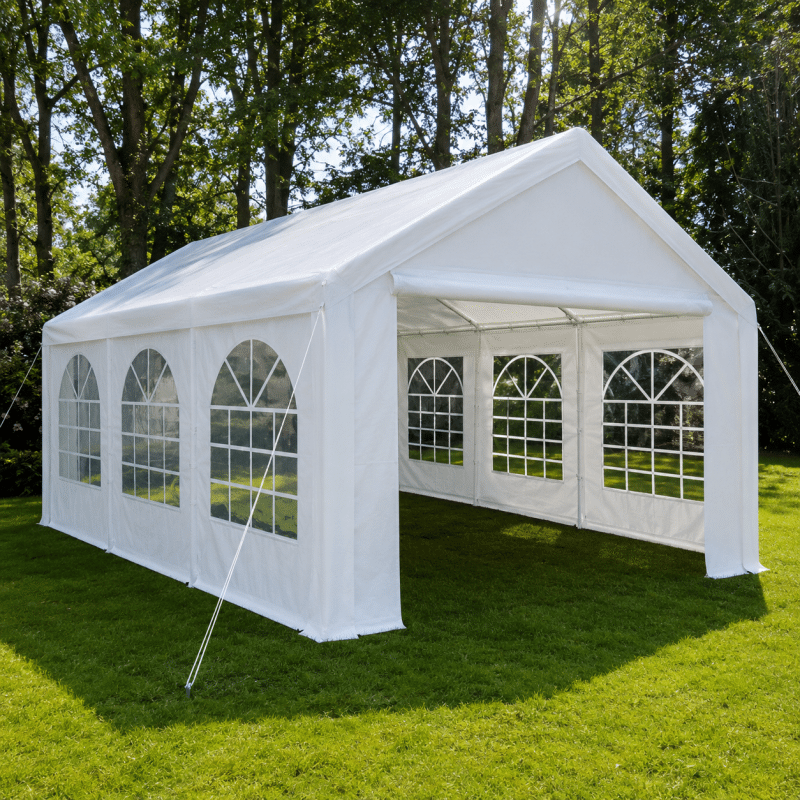 White outdoor event tent with arched window panels set up on a grassy lawn among trees in bright daylight
