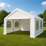 White outdoor event tent with arched window panels on a green lawn under a blue sky