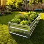 Metal raised planter filled with herbs and flowering plants in a sunlit backyard lawn