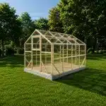 Wood framed greenhouse with clear panels on a concrete base in a grassy yard